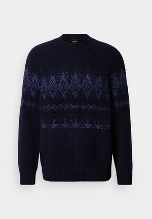 Granatowy sweter z dzianiny z geometrycznym wzorem w różnych odcieniach niebieskiego. Posiada okrągły dekolt oraz prążkowane mankiety i dół.