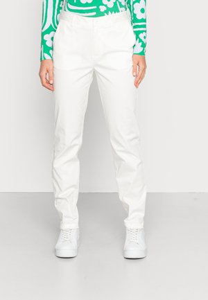 Calças brancas, leves, com um corte descontraído, apresentando uma textura suave e uma cintura padrão. Combinadas com ténis brancos e uma blusa com padrão verde.