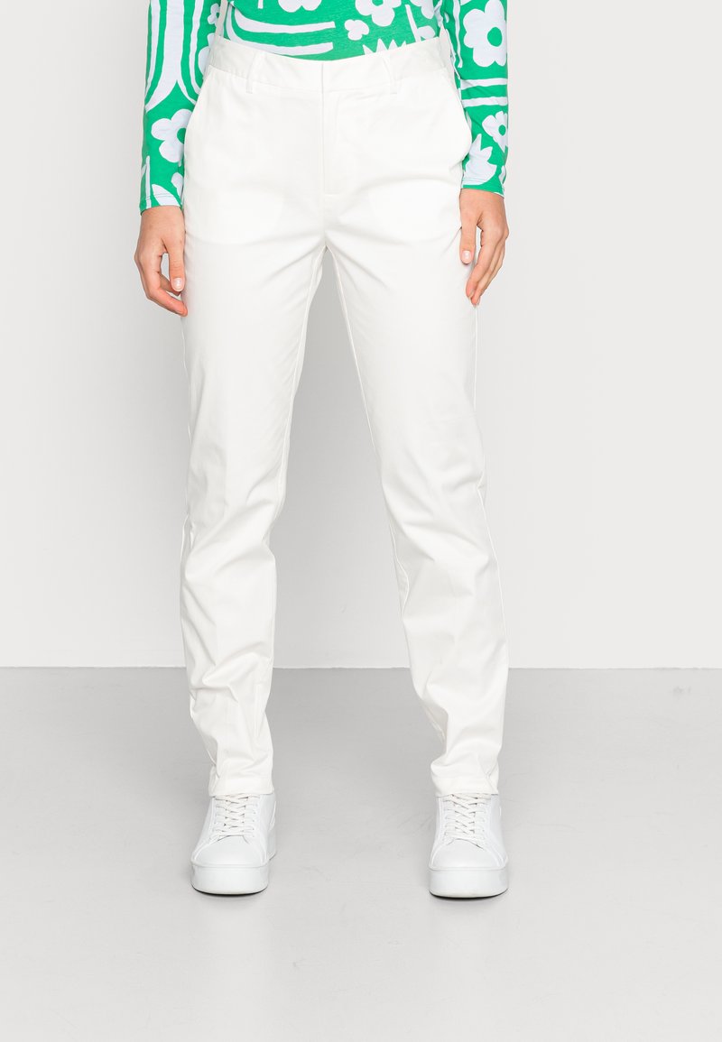 Calças brancas, leves, com um corte descontraído, apresentando uma textura suave e uma cintura padrão. Combinadas com ténis brancos e uma blusa com padrão verde.