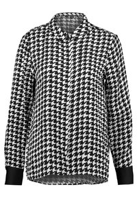 Langærmet bluse i sort og hvid med houndstooth mønster, krave og sorte manchetter. Blødt stof med en afslappet pasform og buet kant.