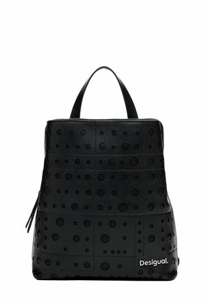 Sac à dos en cuir noir avec motifs circulaires perforés, poignée supérieure, fermeture éclair et petit logo blanc "Desigual" en bas à droite.