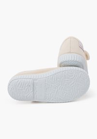 Scarpe in tela beige con suola in gomma bianca testurizzata, dotate di un piccolo etichetta con logo sul lato e design a punta rotonda.