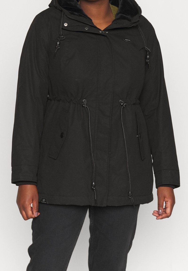 Parka noire avec capuche, taille élastique, poches zippées et doublure intérieure douce. Tissu texturé avec une finition extérieure lisse.