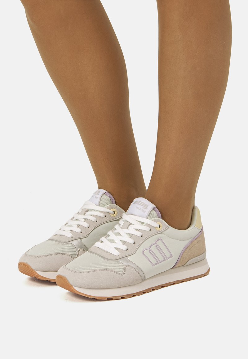 Lichtgrijze sneakers met witte veters en lavendelaccenten. Gemaakt van suède en synthetische materialen, met een bruine rubberen zool.