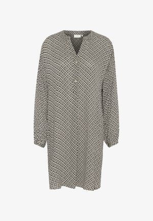 Túnica de patrón en blanco y negro con cuello en V, de mangas largas y corte holgado. Presenta un diseño geométrico y detalles de botones.