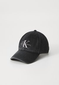 Black denim cap with curved peak, featuring white embroidered "CK" logo and "Calvin Klein Jeans" text. Structured design with a classic fit.
