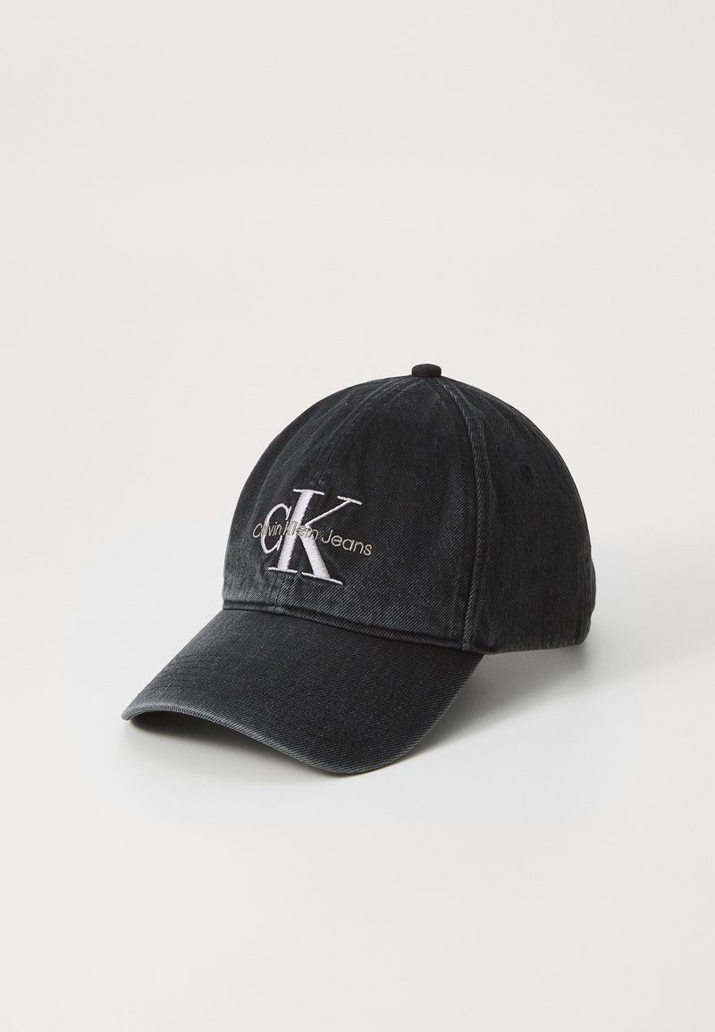Black denim cap with curved peak, featuring white embroidered "CK" logo and "Calvin Klein Jeans" text. Structured design with a classic fit.
