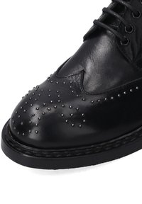 Schwarzer Lederschuh mit Nietenverzierung an der Spitze, runder Form und Schnürdesign; verfügt über eine strukturierte Oberfläche und genähten Rand.