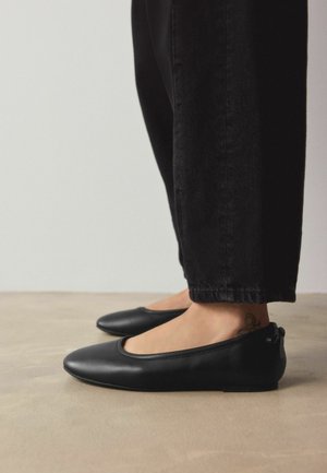Mustat nahkaiset ballerinat, joissa on pyöreä kärki, minimalistinen muotoilu ja pieni korko. Ominaisuuksiin kuuluu pehmeä viimeistely ja hienovaraiset ompelukoristeet.