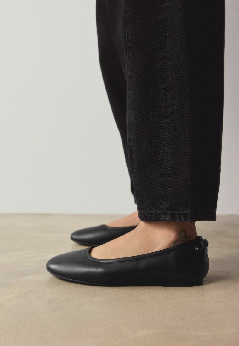 Melni ādas baleta dzīvokļi ar apaļu purngalu, minimālistisku dizainu un mazu papēdi. Raksturīga mīksta apdare un smalkas šuvju akcijas.