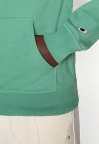 Πράσινο φούτερ με μπροστινή τσέπη και ριμπ μανσέτες. Περιλαμβάνει μικρό λογότυπο στο μα νίκι. Κατασκευασμένο από μαλακό ύφασμα.