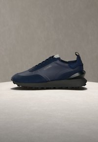 Baskets bleu marine avec semelle noire, design à lacets, languette de talon rembourrée et logo "ICEBERG" sur le côté, présentées sur une surface claire.