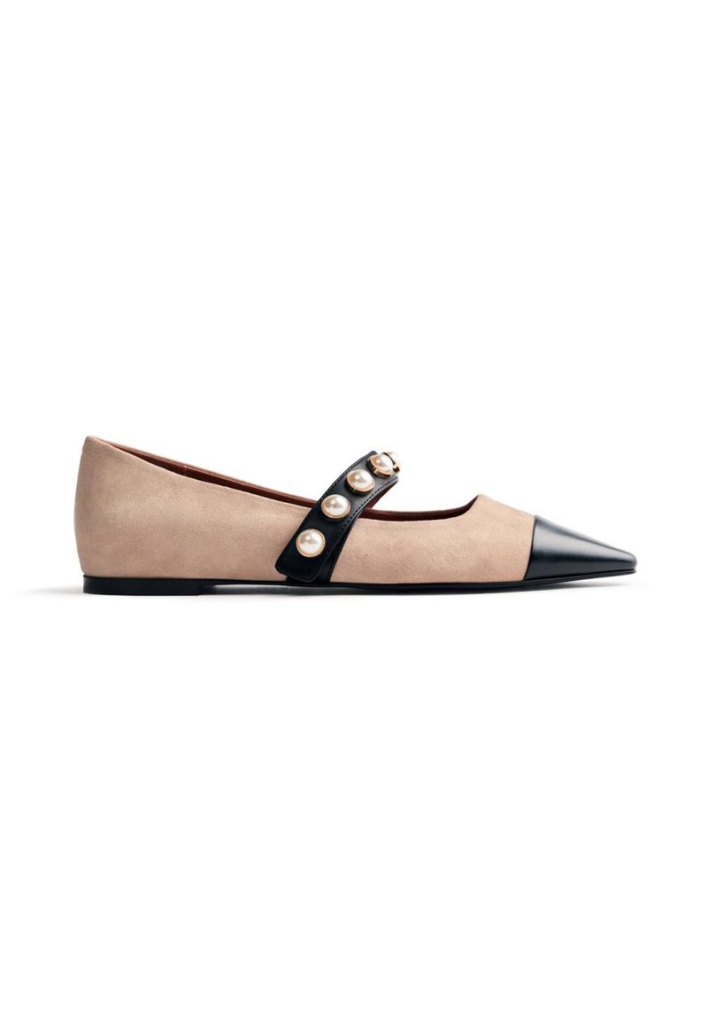 Scarpa piatta beige con punta nera, cinturino nero decorato con grandi perle sulla parte superiore e suola nera bassa.