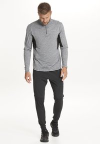 Grå langærmet træningsbluse med halvlukket hals, sorte sidepaneler; sorte træningsbukser; sorte sneakers; sporty design.
