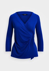 Blue long-sleeve wrap top with a V-neck, featuring gathered fabric at the waist and a tie detail on the side. Smooth, stretchy material.