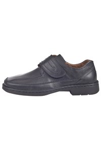 Sort læder slip-on sko med velcro-strop, der har syede detaljer, en rund tå og en tekstureret gummisål.