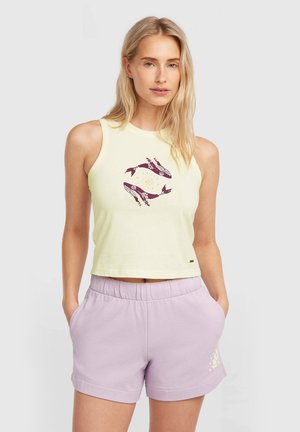 Haut court sans manches jaune clair avec un motif graphique circulaire en bordeaux et jaune. Associé à un short lavande avec une impression subtile.