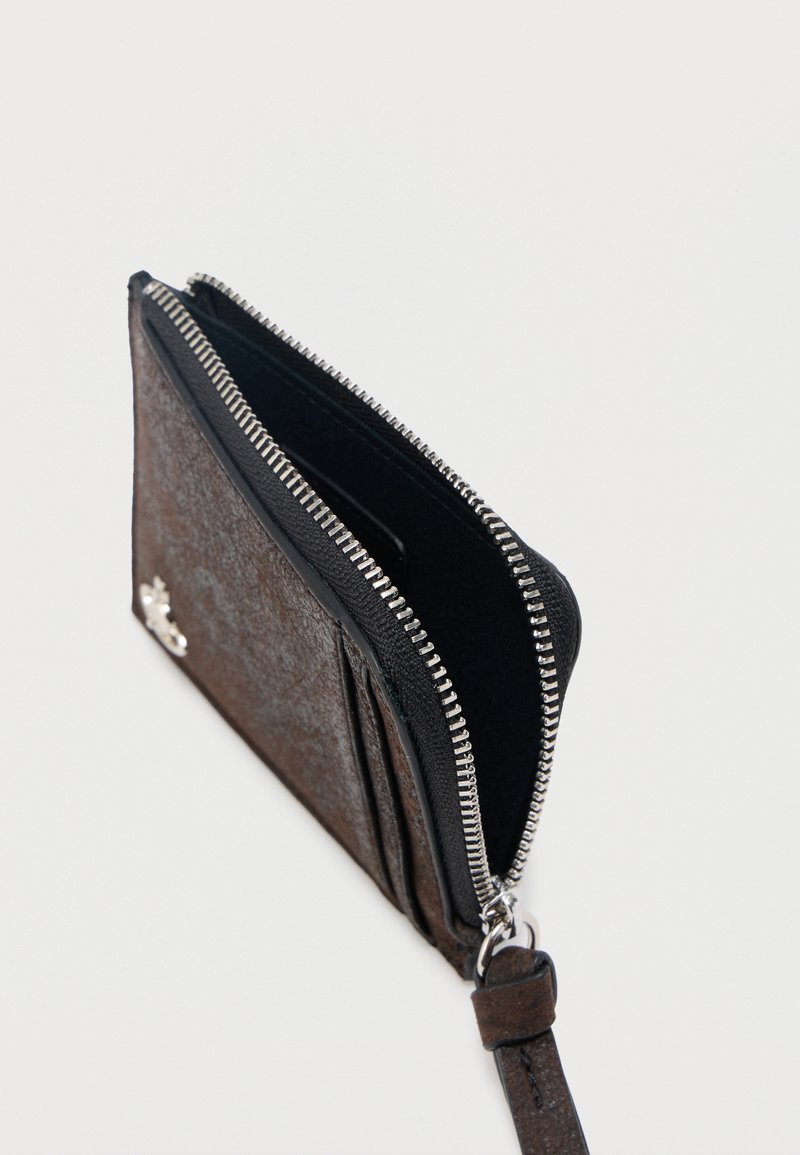 Porta carte in pelle marrone scuro con cerniera argentata parzialmente aperta e cinturino da polso attaccato a un anello metallico.