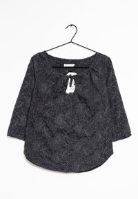 Blusa nera con ricami floreali. Presenta un collo a giro, maniche a tre quarti e una vita arricciata, realizzata in tessuto testurizzato.