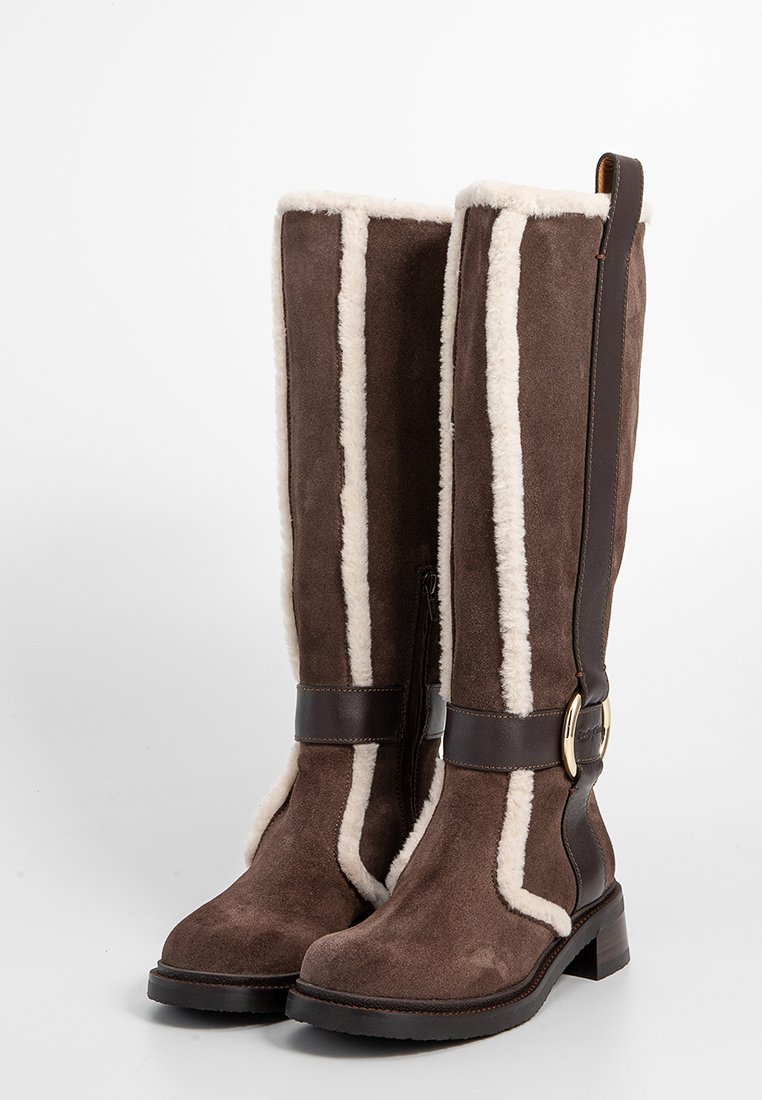 Bruine suède kniehoge laarzen met witte bontafwerking, leren accenten en een goudkleurige gesp. Stevige blokhak voor stabiliteit.