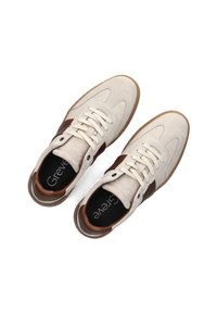 Witte suede sneakers met bruine leren accenten, ronde neus en vetersluiting. Voorzien van een gevoerd voetbed en een gepatineerde rubberen zool.