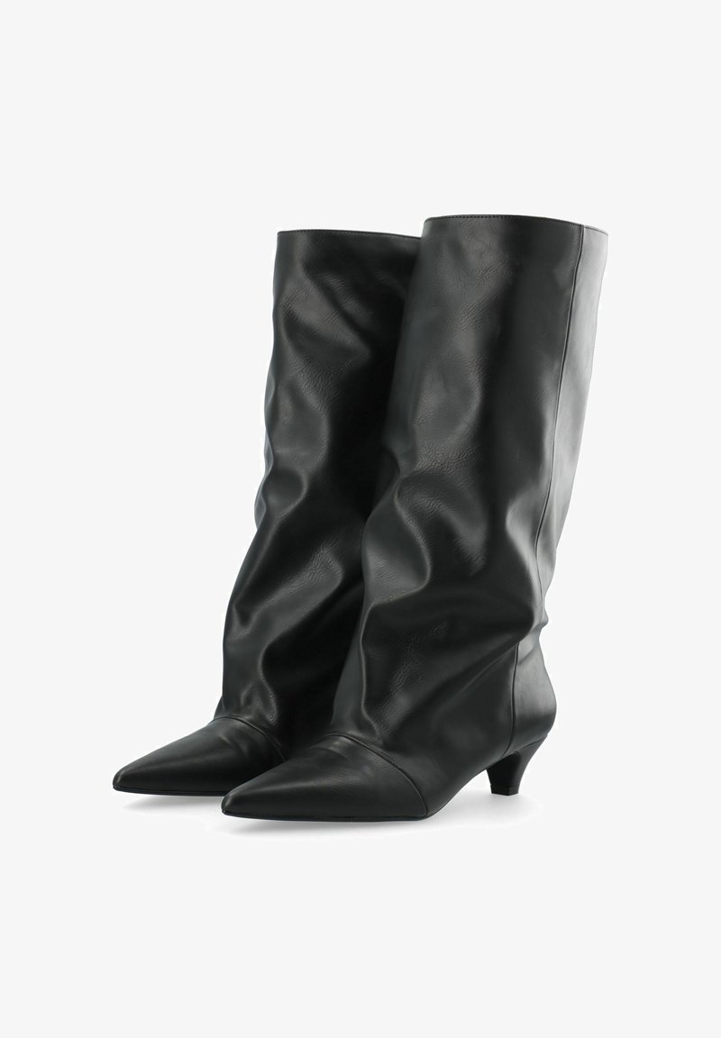 Paire de bottes en cuir noires montantes jusqu'au genou, à bouts pointus et petits talons kitten sur fond blanc.