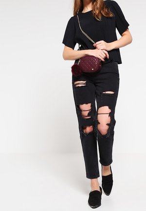 Top nero a maniche corte a coste con una borsa a tracolla trapuntata bordeaux con catenella. Jeans neri con grandi strappi. Scarpe nere slip-on.