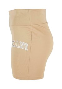 Beige, aansluitende skort met een hoge tailleband. Voorzien van een zijprint "KANI" in het wit. Gemaakt van een zachte, rekbare stof met een gladde textuur.