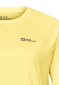 Gelbes Langarmshirt aus strukturiertem Stoff, mit Rundhalsausschnitt und einem kleinen dunklen Logo auf der oberen linken Seite.