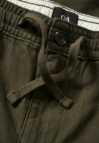 Krótkie spodenki w kolorze oliwkowej zieleni z zapięciem na sznurek, guzik z kwiatowym wzorem oraz kontrastującym białym elastycznym pasem w talii.