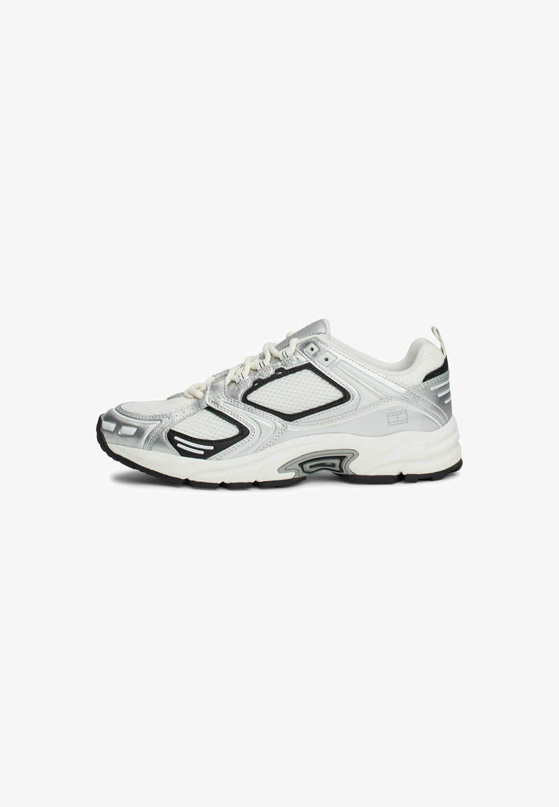 Sneakers z białej siateczki i srebrnymi syntetycznymi detalami, czarnymi akcentami oraz teksturowaną podeszwą. Posiadają wyraźne sznurowanie i pętlę z tyłu.
