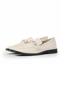 Mocasines de cuero blanco con detalles en dorado, punta afilada y suela texturizada. Diseñados con un tacón bajo y plano para mayor confort.
