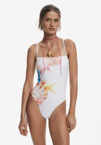 Maillot de bain une pièce blanc avec un design coloré de coquillage et d'étoile de mer, bretelles fines et taille haute. Texture lisse avec des accents vibrants.