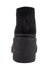 Black suede ankle boots with a chunky textured platform sole, featuring a rounded upper and minimal stitching detail.