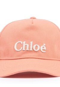 Gorra de béisbol color melocotón hecha de tela de algodón, con el texto "Chloé" bordado en blanco en el frente. Textura suave, forma estructurada y visera precurvada.