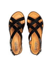 Zwarte leren sandalen met kruisende bandjes, een gevoerde lichtbruine inlegzool en een metalen gesp. Getextureerde stiksels langs de randen.