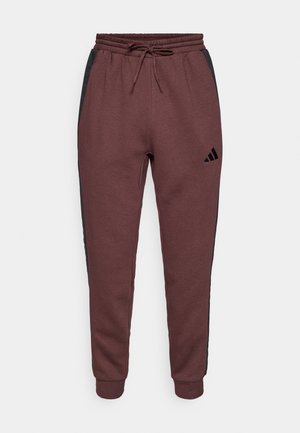 Pantalones de chándal color gris burdeos con paneles laterales negros, cintura elástica y cordón ajustable. Presenta el logo de Adidas en la parte inferior de la pierna izquierda.