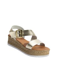 Sandales plateforme métalliques dorées avec des brides croisées, un accent boucle et une base tissée semblable à du jute ; semelle intérieure beige et semelle en caoutchouc blanche.