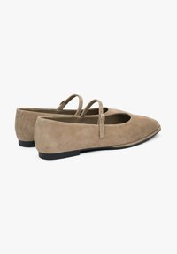 Beżowe zamszowe baleriny z okrągłym noskiem, podwójnymi wąskimi paskami na podbiciu oraz płaską, czarną gumową podeszwą.