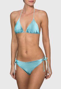 Ensemble de bikini turquoise à pois, comprenant un haut triangle et un bas à nouer sur les côtés. Fabriqué en tissu brillant et lisse avec des bretelles ajustables.