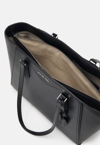Mustat nahkainen olkalaukku, jossa on vetoketjullinen sulku, teksturoitu ulkopinta ja vaaleanbeige sisävuori. Varustettu kahdella kahvalla ja hopeanvärisillä metalliosilla.