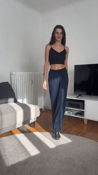 Črn skrajšan top brez rokavov in mornarsko modri široki hlače s širjenjem in vrvico. Model nosi črne superge, stoji na svetli preprogi v preprostem notranjem okolju.