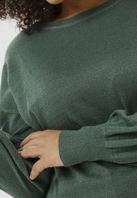 Groene, lang-sleeve gebreide trui met een subtiele glans, voorzien van een ronde hals en ribgebreide manchetten. Zachte textuur met een losse pasvorm.