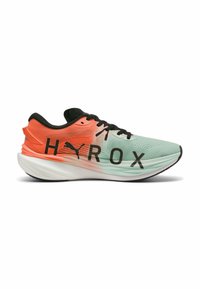 Zapatilla de running ligera en verde menta con acentos en coral, con un upper de malla texturizada y bold lettering negro "HYROX" en el costado.