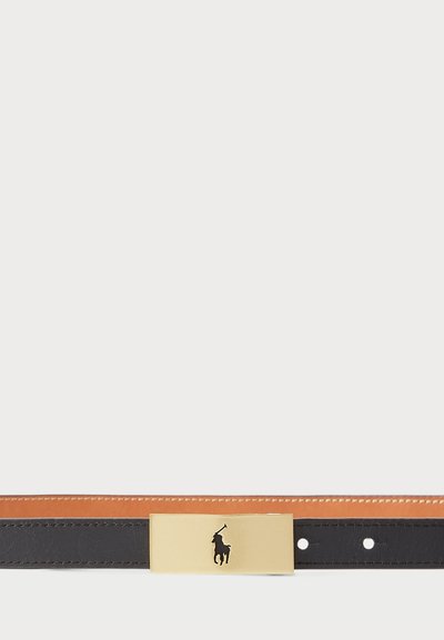 Melnā ādas josta ar brūnu oderi un zelta metāla sprādzi, kurai ir melns zīmols. Sprādze ir taisnstūrveida ar gludu virsmu.