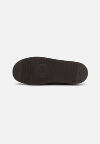 Suela de zapato de goma negra con estrías horizontales, puntera redondeada y detalle de logo en relieve. Talla 42 impresa en el lateral. Textura suave.