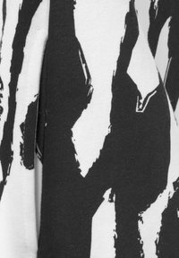 Black and white patterned fabric with abstract brushstroke design, featuring a soft texture and contrasting colors. Close-up detail.