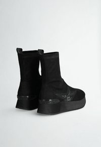 Stivaletti neri alla caviglia in camoscio, con un design a stella e decorazioni, un tacco patterned e linguette per indossarli facilmente.