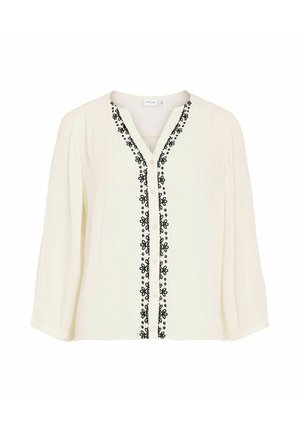 Blouse blanche à manches longues avec col en V, broderie florale noire le long de la patte de boutonnage avant, et coupe ample.