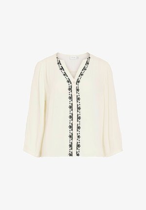 Blouse blanche à manches longues avec col en V, broderie florale noire le long de la patte de boutonnage avant, et coupe ample.